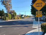 Yellow Street sign of speed table 20 miles per hour with with crosswalk lines at Clares and 42nd